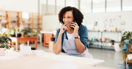 Phone call, thinking and woman in workshop for pottery inventory, sculpture idea or order clay supply. Ceramic art, happy person and talking with technology for insight, planning and creative craftの写真素材