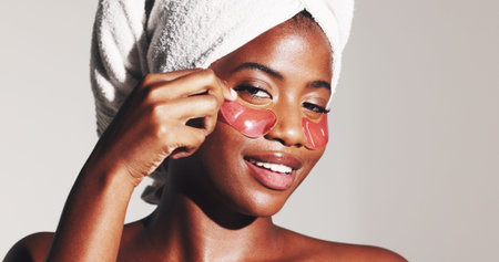 Portrait, beauty and eye patches with black woman in studio for dermatology, self care and spa treatment. Glow, collagen mask and skincare with person on white background for shine and facialの写真素材