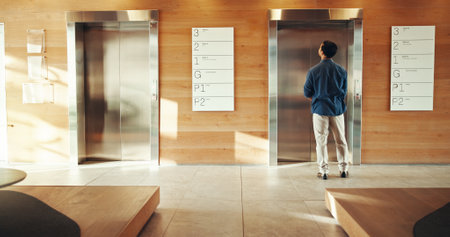 Business, man and waiting at elevator in building for floor request, meeting appointment and destination. Back, professional person and office lift for work arrival, departure and morning routineの写真素材