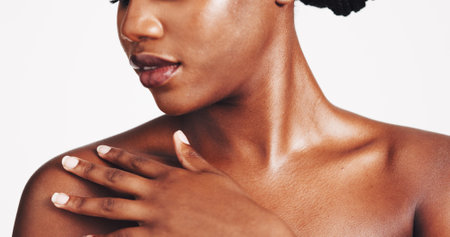 Shoulder, skincare and touch with black woman in studio for body care, hydration and beauty routine. Shine, glow and dermatology with closeup of person on white background for cosmetics and collagenの写真素材