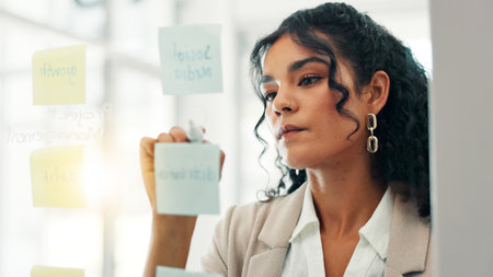 Business, woman and writing on glass in office for planning, ideas notes and schedule update. Female person, board and brainstorming with information, tasks reminder and agenda for project deadlineの写真素材