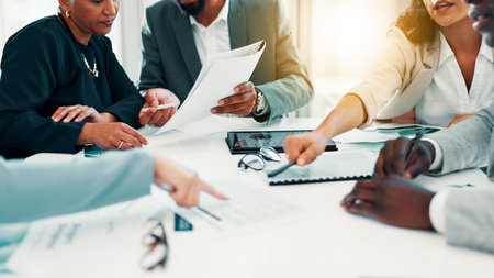 Business people, paperwork and hands with discussion in meeting for finance forecasting, data analysis or planning. Financial analyst, teamwork or pointing to revenue statement for capital allocationの写真素材