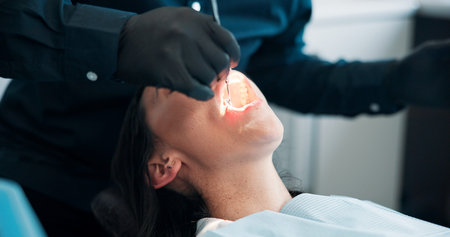 Hands, light and mouth of patient with dentist in office for checkup, operation or surgery....