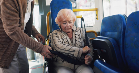 Elderly woman, wheelchair and seatbelt in bus with partner, safety and helping hand for travel in town. Senior couple, support and person with disability, mobility aid or retirement with trip in cityの写真素材