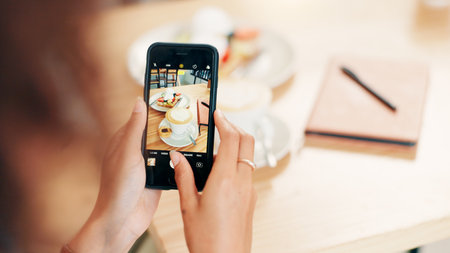 Phone screen, hands and photography of breakfast, cafe or recommendation for restaurant on website. Coffee shop, influencer and person with mobile for picture, above or review of food on social mediaの写真素材