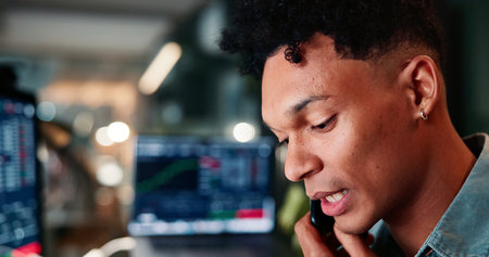 Phone call, computer and man in office with trading at night for client investment account. Technology, communication and male financial analyst with stock market risk analysis in workplace.の写真素材