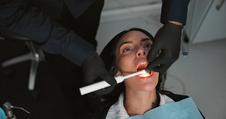 Hands, medical and mouth of patient with dentist in office for checkup, operation or surgery. Appointment, healthcare or oral exam with medicine professional and woman at clinic for dental hygieneの写真素材
