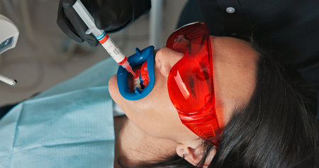 Cleaning, mouth and visor on patient with dentist in office for checkup or dental procedure. Healthcare, oral surgery or teeth whitening with medicine professional and woman at clinic for dentistryの写真素材