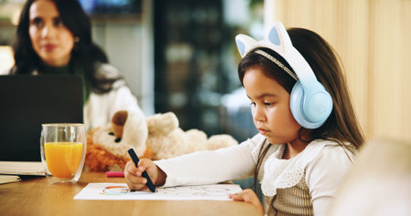 Drawing, remote work or mom with kid, homework or single parent for education or homeschool lesson. Headphones, mother and daughter colouring on paper for learning activity, student and sketchingの写真素材