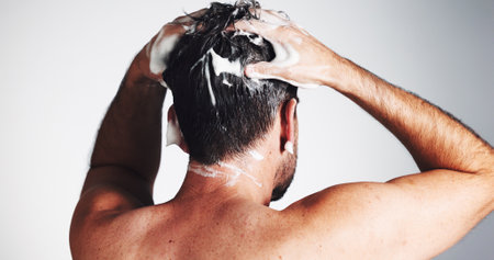 Shampoo, hair care and beauty with man in studio for shower, scalp health and dandruff treatment. Growth, texture and grooming with person on white background for cosmetics, shine and cleaningの写真素材