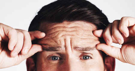Forehead, wrinkles and beauty with man in studio for anti aging, dermatology and collagen product. Skincare, spa treatment and mature with closeup of person on white background for cosmeticsの写真素材