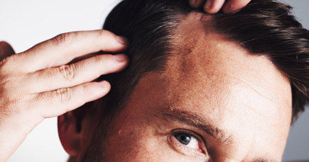 Hairline, growth and closeup with man in studio for scalp inspection, beauty and alopecia treatment. Grooming, self care and dandruff with mature person on white background for clean and textureの写真素材