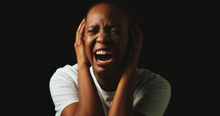 Woman, screaming and stress in studio with anxiety, panic and mental health by black background. African girl, crying and shouting with depression, frustrated and lonely with trauma, ptsd and darkの写真素材