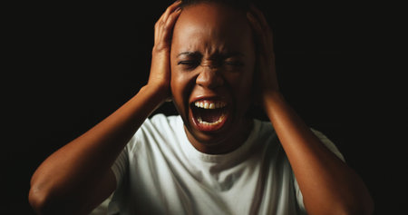 African woman, screaming and stress in studio with anxiety, panic and mental health by black background. Person, crying and shouting with depression, frustrated and lonely with trauma, ptsd and darkの写真素材