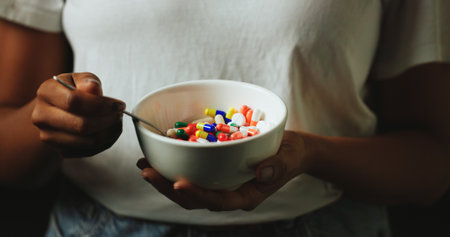 Hands, bowl and pills for addiction in studio with eating for mind altering drugs by black background. Person, capsule and illegal medicine with opioid crisis, mood and spoon with chemical compoundの写真素材