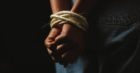 Black background, studio and hands of person with rope for prisoner, hostage and victim. Bondage, mockup space and closeup for human trafficking, domestic violence and crime for slavery or traumaの写真素材