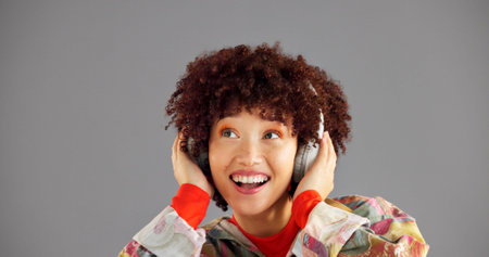 Headphones, thinking and woman in studio, listening to music and sound on grey background. Person, mockup space or happy model with confidence, fashion or headset with audio, streaming radio or smileの写真素材