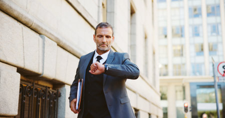 Businessman, walking and checking watch in city for travel delay, schedule or running late. Man, attorney or lawyer with wristwatch for time, deadline or court case appointment in an urban townの写真素材