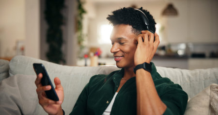 Headphones, smile and phone with man on sofa for social media, movie platform and streaming service....