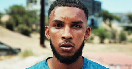 Portrait, man or athlete sweating in stadium of outdoor fitness training, cardio workout or sports exercise. Race track, confident or face of tired runner on break for breathing in running practiceの写真素材