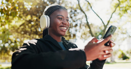Park, athlete and woman with smartphone, headphones and tracking progress of exercise on app and...