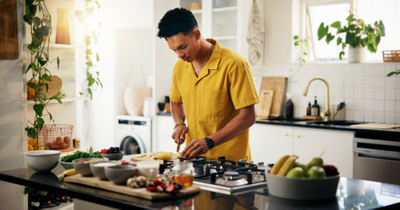 Cooking, concentration and cutting with man in kitchen of home for hobby, meal prep or nutrition. Ingredients, passion and recipe with person in apartment for diet, health or supper as culinary chefの写真素材