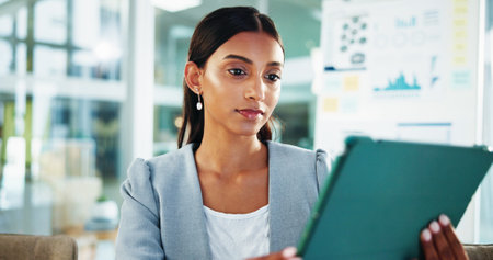 Reading, thinking and business woman with tablet for accounting, economy update or finance report in office. Scroll, online and financial advisor with portfolio advice, research graphs or investmentの写真素材