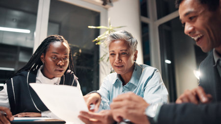 Documents, proposal and business people in meeting for financial review, budget report and working late. Corporate office, night and workers with paperwork for collaboration, strategy and planningの写真素材