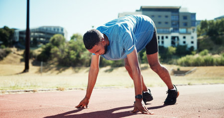 Start, running and athlete or man on race track for fitness, training and cardio performance. Health, marathon and sports runner with person and outdoor stadium for competition, ready and workoutの写真素材
