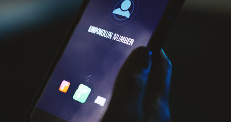 Phone call, screen or hand with unknown number, alert or icon display for phishing scam contact at night. Person, dark and hacker with digital graphic, mobile user and tech for incoming anonymous IDの写真素材