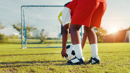 Playing, soccer and preparing for kick, children and player with skills for game, talent and cardio. Outdoor, football and kids with sportswear for match, growth and development of youth or fitnessの写真素材