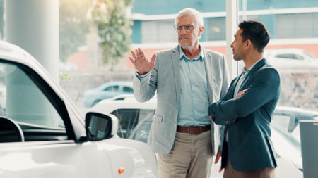 Car dealership, report or salesman with customer talking for vehicle history, details or features. Transport, people or seller with client in showroom for negotiation, travel or decision for purchaseの写真素材