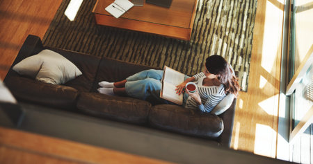 Above, woman and reading book with tea at house for literature, fantasy novel and weekend break....