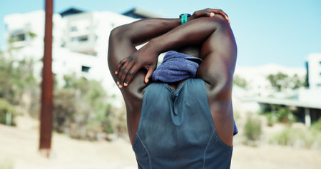 Athlete, stretching and back of black man for sports, fitness competition and challenge outdoor. Male person, warm up and workout to prepare muscle, arms and run for exercise and performanceの写真素材
