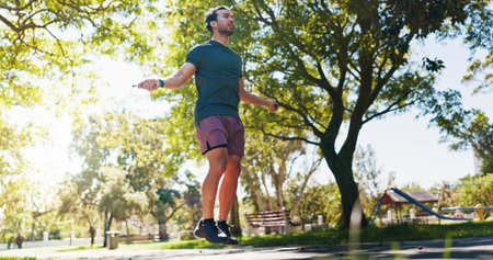 Fitness, jump rope and health with man in park for cardio workout, wellness and energy. Challenge,...