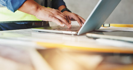 Man, laptop and hands with typing for construction, floor plan inspection and building renovation of development. Engineer, technology and project management with maintenance for infrastructureの写真素材