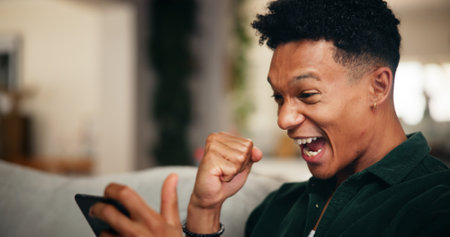 Gaming, phone and winner with man on sofa for esports streaming, cyber sport league and fist pump. Celebration, gamer success and app platform with excited person in home for online tournamentの写真素材