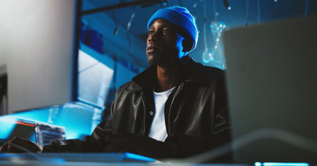 Black man, hacker and reading on pc at night for programming, cyber attack and online information. Male person, computer and research for website phishing, data protection and criminal for fraud riskの写真素材