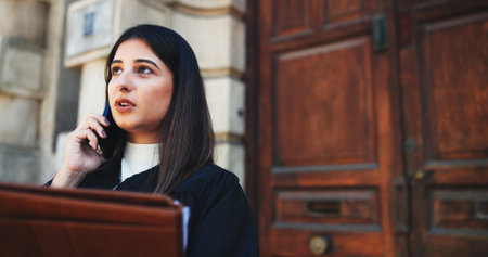 Phone call, lawyer and woman in city, conversation and documents with legal aid service. Outdoor, employee and attorney with smartphone, discussion and folder for court case, talking and negotiationの写真素材