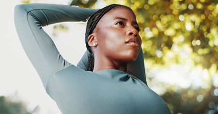 Fitness, exercise and black woman with stretching at park to start workout, cardio performance and getting ready. Low angle, athlete and arm warm up in nature for training and muscle tension reliefの写真素材
