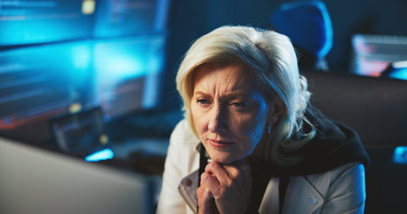 Thinking, computer and business woman at night for programming, coding and cybersecurity. Professional, thoughtful and mature person on pc for website development, online research and softwareの写真素材