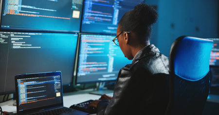 Hacker, online and woman with computer, night and data for cyber espionage, system and phishing in office. Screen, typing and black person with tech for ransomware, spy and hacking for fraud or scamの写真素材