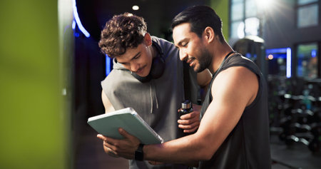 Men, personal trainer and tablet with talking at gym with smile, sign up and listening with exercise...