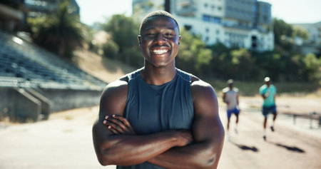 Runner, man and happy with arms crossed at stadium for sprint competition, fitness workout and race practice. Athlete, portrait and ready for running track outdoor with exercise, confidence and prideの写真素材