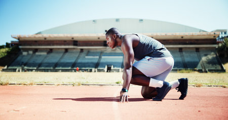 Ready, fitness and athlete or black man on running track for sports, training and cardio performance. Health, marathon and runner with person and outdoor stadium for competition, start and workoutの写真素材