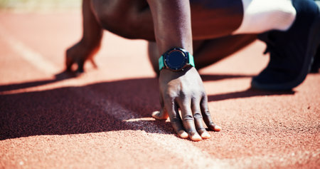 Person, hands and runner ready at starting line for race, sprint or new record time at stadium. Closeup, athlete or fitness with wrist watch for sport marathon, beginning challenge or competitionの写真素材