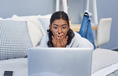 Shock, laptop and woman on bed with scam, phishing or fraud online transaction at apartment....