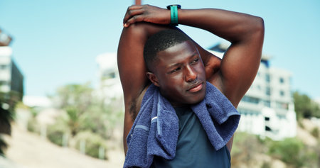 Stretching, runner and fitness with black man in stadium for marathon training, health and cardio challenge. Warm up, competition and exercise with person for sports athlete, workout and wellnessの写真素材