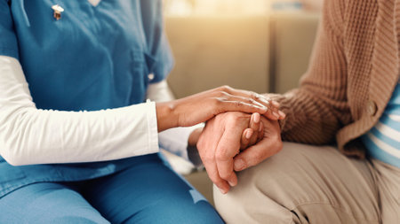 Elderly patient, nurse and hands with care on sofa for empathy or understanding at retirement home. Closeup, caregiver and help with senior person for assisted living, sympathy or support at houseの写真素材