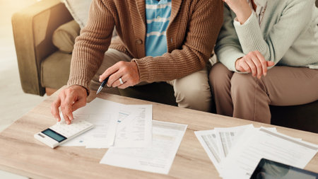Elderly couple, hands and calculator with documents for budget planning, finance or audit at home. Senior, man and woman with paperwork, bills or expenses for financial calculation or accountingの写真素材